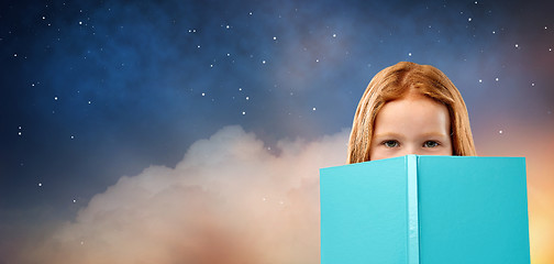 Image showing red haired girl behind book over starry night sky