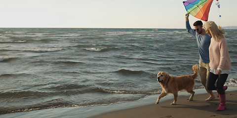 Image showing couple with dog having fun on beach on autmun day