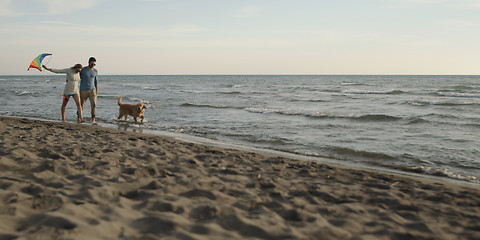 Image showing couple with dog having fun on beach on autmun day