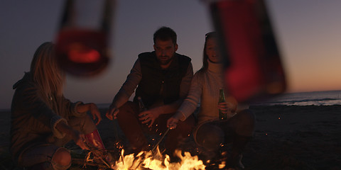 Image showing Young Friends Making A Toast With Beer Around Campfire at beach