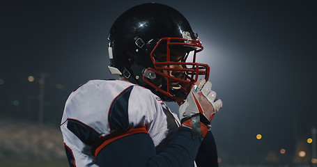 Image showing American Football Player Putting On Helmet on large stadium with