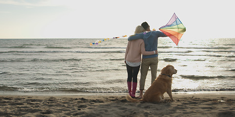 Image showing couple with dog having fun on beach on autmun day