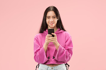 Image showing Young beautiful woman using mobile phone studio on pink color background