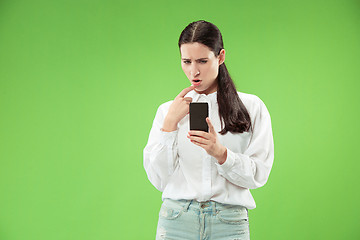 Image showing Young beautiful woman using mobile phone studio on green color background