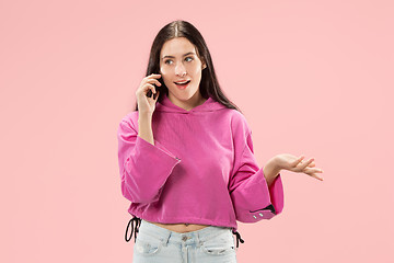 Image showing Young beautiful woman using mobile phone studio on pink color background