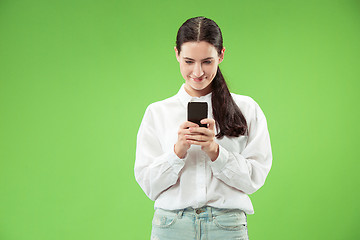 Image showing Young beautiful woman using mobile phone studio on green color background