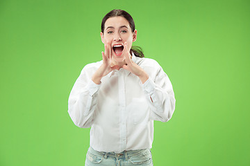 Image showing Isolated on green young casual woman shouting at studio