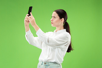 Image showing Portrait of a happy smiling casual girl showing blank screen mobile phone isolated over green background