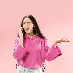 Image showing Young beautiful woman using mobile phone studio on pink color background
