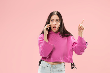 Image showing Young beautiful woman using mobile phone studio on pink color background