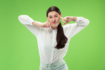 Image showing The squint eyed woman with weird expression isolated on green