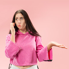 Image showing Young beautiful woman using mobile phone studio on pink color background