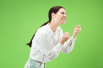 Image showing Portrait of an angry woman looking at camera isolated on a green background