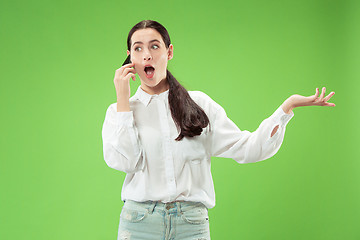 Image showing Young beautiful woman using mobile phone studio on green color background