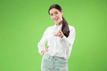 Image showing The happy business woman point you and want you, half length closeup portrait on green background.