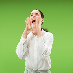 Image showing Isolated on green young casual woman shouting at studio