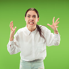 Image showing Portrait of an angry woman looking at camera isolated on a green background