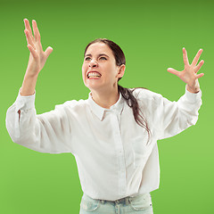 Image showing Beautiful female half-length portrait isolated on green studio backgroud. The young emotional surprised woman