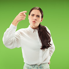 Image showing Beautiful female half-length portrait isolated on green studio backgroud. The young emotional surprised woman