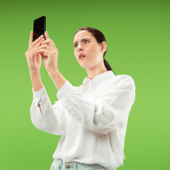 Image showing Young beautiful woman using mobile phone studio on green color background