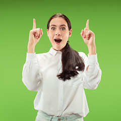 Image showing Beautiful woman looking suprised isolated on green