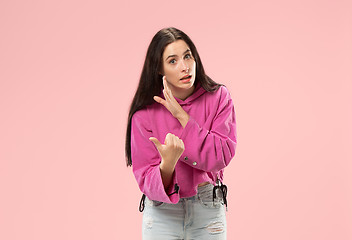 Image showing The young woman whispering a secret behind her hand over pink background