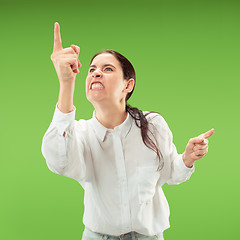 Image showing Beautiful female half-length portrait isolated on green studio backgroud. The young emotional surprised woman