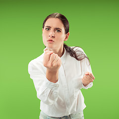 Image showing Portrait of an angry woman looking at camera isolated on a green background