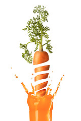 Image showing Falling slices of cut carrot to a glass of juice.