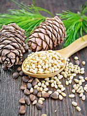 Image showing Cedar nuts peeled in spoon on dark board