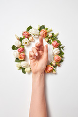 Image showing Female\'s hand inside wreath from fresh natural roses flowers.