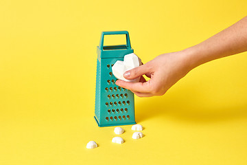 Image showing Woman\'s hand holds plaster heart against kitchen grater.