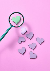 Image showing Big green heart under magnifying glass among other hearts.