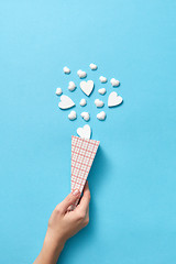 Image showing Woman\'s hand with paper cone of small plaster hearts.