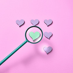 Image showing Magnifying glass above hearts pattern.