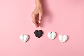 Image showing Woman\'s hand puts black heart around white hearts.