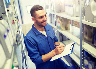 Image showing smiling auto mechanic with clipboard at car shop