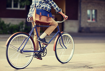 Image showing young hipster man with bag riding fixed gear bike