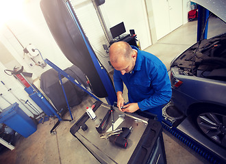 Image showing mechanic man with wrench repairing car at workshop