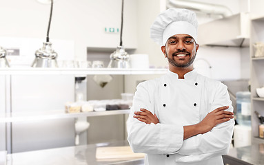 Image showing happy indian chef in toque at restaurant kitchen