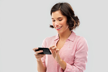 Image showing young woman in striped shirt using smartphone