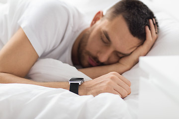 Image showing close up of man with smart watch sleeping in bed