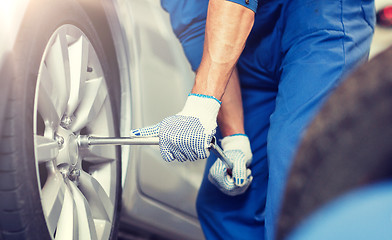 Image showing mechanic with screwdriver changing car tire