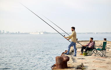 Image showing happy friends with fishing rods on pier