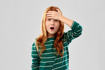 Image showing shocked red haired girl holding to her head