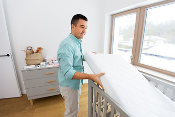 Image showing father arranging baby bed with mattress at home