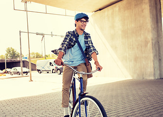 Image showing young hipster man with bag riding fixed gear bike