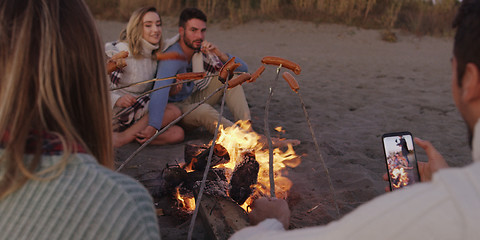 Image showing Group Of Young Friends Sitting By The Fire at beach