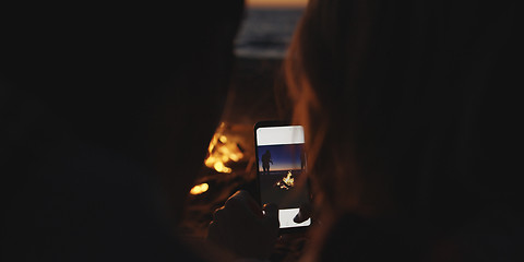 Image showing Couple taking photos beside campfire on beach