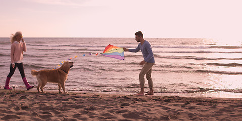 Image showing couple with dog having fun on beach on autmun day